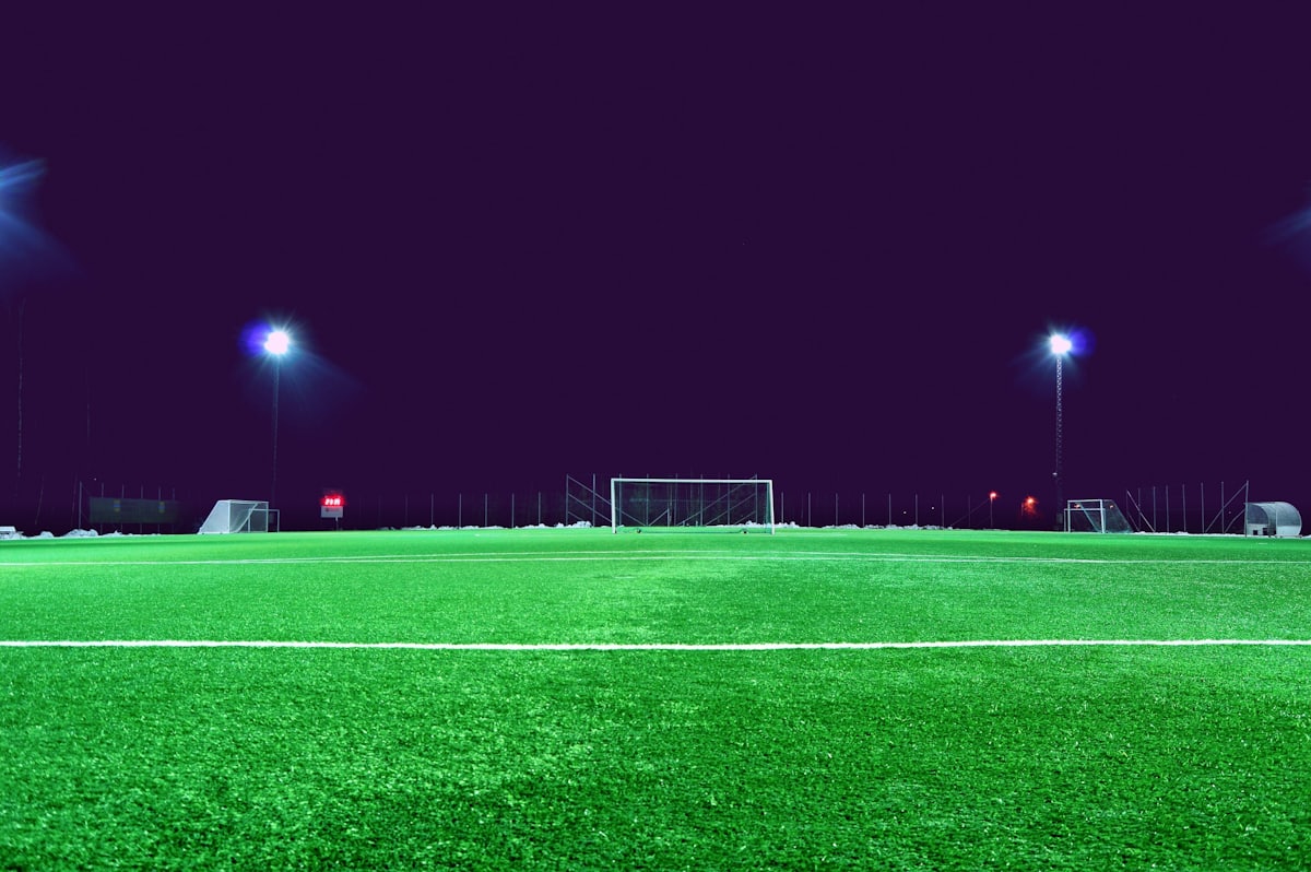 Stadion sepak bola di malam hari dengan lampu sorot menyala